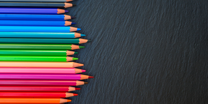 Line of coloured pencils on black chalk board